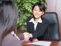 Asian businesswoman interacting at a desk with a female OAPIA representative