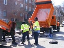 Street Repair Street Repair - a DDOT crew working next to an orange dump truck and an orange asphalt depositor repairing a city street